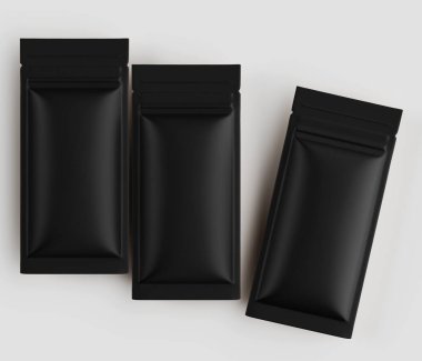 Üç siyah, dikdörtgen, folyo kesesi hafif örtüşen düz bir düzende, açık gri arkaplana karşı düzenlenmiştir..