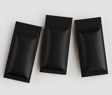 Üç siyah folyo kesesi düz beyaz arka plan üzerinde düz bir kompozisyonda düzenlenir. Keselilerin siyah bir kaplaması ve dikdörtgen şeklinde bir şekli var. Bu da paket aperatifleri veya diğer yiyecek öğeleri için kullanılabileceklerini gösteriyor. Çakmak.