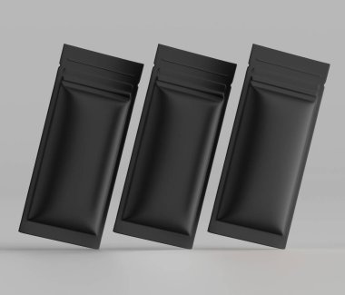 Gıda veya diğer ürünler için muhtemelen üç siyah folyo kesesi veya ambalaj kağıdı, nötr gri arka plana karşı hafifçe açılı, süzülen bir şekilde sunulmaktadır. Kesesinde parlak ya da pürüzsüz bir mat yüzey dokusu var. Işıklandırma nötr ve Eve