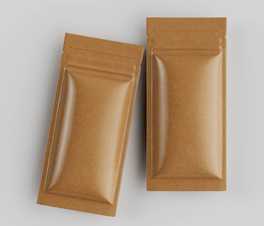 İki dikdörtgen, açık kahverengimsi altın ambalaj kesesi, tarafsız gri arka plana karşı tepeden tırnağa bir perspektiften sergileniyor. Poşetlerin pürüzsüz, hafif parlak bir yüzeyi var. Bu da kaplamalı ya da kaplamalı bir malzeme olduğunu gösteriyor. Şekilleri ve tasarımları