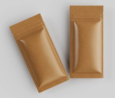 İki açık kahverengi, dikdörtgen, esnek ambalaj kesesi nötr gri bir yüzeye yerleştirilmiştir. Keseler kağıttan ya da kartondan yapılmış gibi görünüyor, hafif parlak bir kaplaması var. Düz ve mühürlü kenarları var. Işıklandırma yumuşak ve düz, Casti.