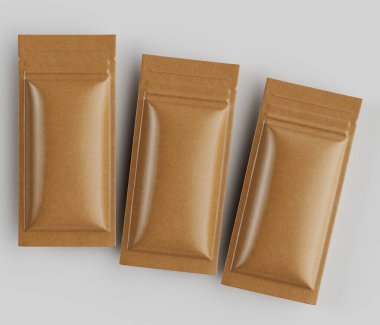 Açık kahverengi, dikdörtgen, folyoyla mühürlenmiş üç kese, açık gri arka plana karşı sarsıcı ve hafifçe örtüşen bir şekilde düzenlenmiştir. Kese boş gibi görünüyor, ya da üniforma, açık ten tozu ve bir çeşit yiyecek paketi gibi görünüyor.