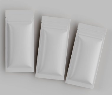 Muhtemelen folyo veya plastikten yapılmış üç boş beyaz kese açık gri arka planda hafifçe örtüşen bir şekilde düzenlenmiştir. Kese dikdörtgen şeklinde ve pürüzsüz görünüyor. Aydınlatma dengeli ve tepede, belirgin bir shad yok.