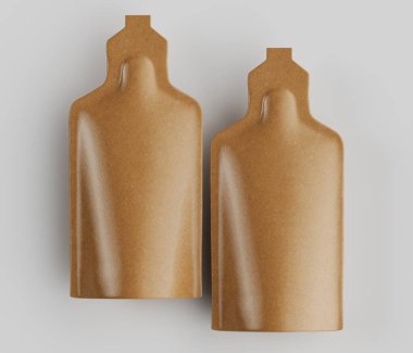Açık gri bir yüzeye, muhtemelen bir stüdyo arka planına yerleştirilmiş özdeş iki açık kahverengi kese var. Keselerin pürüzsüz, hafif parlak bir kaplaması var ve küçük bir şişeyi andıran bir kapağı olan dikdörtgen şeklinde. Aydınlatma düz ve tepede.