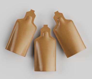 Üç açık kahverengimsi altın rengi, yuvarlak kaplamalı dikdörtgen keseler, parlak beyaz bir arka planda gevşek, hafifçe baş aşağı sarsıcı bir kompozisyonda düzenlenmiş. Poşetlerin pürüzsüz, parlak yüzeyleri ürünler için olası bir ambalaj malzemesi olduğunu gösteriyor.