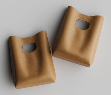 İki açık kahverengi deri çanta, bir tepeden çekimde tarafsız bir arkaplana karşı gösteriliyor. Poşetler basit tasarlanmış. Kesme saplı ve dikdörtgen şekilli. Işıklandırma yumuşak ve hatta derinin dokusunu vurguluyor. 