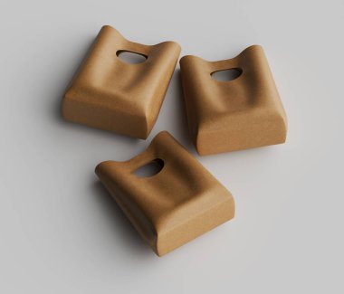 Açık gri bir yüzeye gelişigüzel yerleştirilmiş üç açık bej alışveriş çantası. Çantaların dikdörtgen şeklinde ve kesme sapı var. Poşetler biraz buruşuk görünüyor, doğal, cilalanmamış bir görünüm veriyor. Işıklar eşit ve nötrdür.