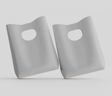 Bir stüdyo ortamında iki açık gri plastik alışveriş torbası sunuluyor. Çantalar hafif açılı, dinamik bir düzende, açık gri bir arkaplana karşı yerleştirilmiş. Torbaların sapları kesilmiş, basit ve düz şekilleri var. Bir c