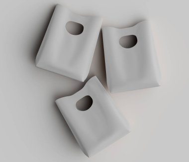 Üç açık gri, basit kağıt torba düz, beyaz bir yüzeye yerleştirilmiştir. Torbaların pürüzsüz, mat bir dokusu var ve her iki tarafında da sapları için tek bir dairesel kesik var. Çantalar gevşek bir grupta, birbirlerine karşı açılılar. 