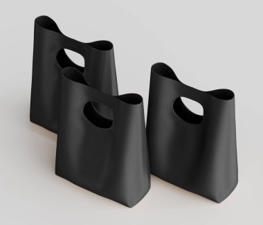 Bir stüdyo ortamında üç siyah alışveriş çantası sunuluyor. Poşetler pürüzsüz, mat bir malzemeden yapılmış ve üst üste binen bir kompozisyonda düzenlenmiş. Çantaların tasarımında eşsiz kapı kolları var. Tarafsız, parlak...
