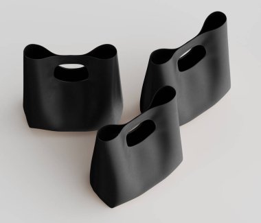 Bu resimde düz ve açık arkaplan üzerine kurulmuş üç minimalist siyah çanta var. Entegre sapları ve temiz çizgileriyle çantalar modern, heykel estetiği sergiliyor. Işıklandırma bir stüdyo ortamını işaret ediyor.