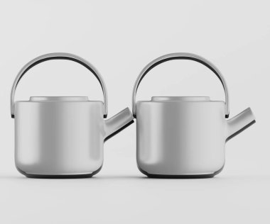 İki modern, açık gri çaydanlık açık gri bir zemine karşı sergileniyor. Çaydanlıkların basit yuvarlak şekilleri ve pürüzsüz yüzeyleri var. Tarz çağdaş görünüyor. Işıklandırma nötr ve pürüzsüz dokuyu ve yansıtmayı vurgular