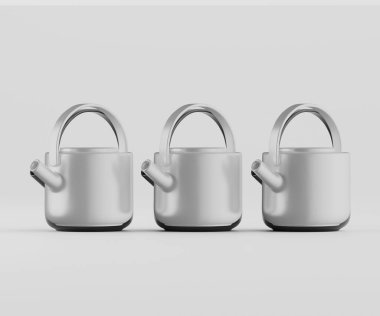 Üç modern çaydanlık kapalı bir stüdyo ortamında sergileniyor. Çaydanlıklar metaliktir, açık gri veya gümüş renktedir ve pürüzsüz, parlak yüzeylere sahiptir. Düz bir çizgide düz, açık gri bir zemine doğru konumlanmışlar. Şey...