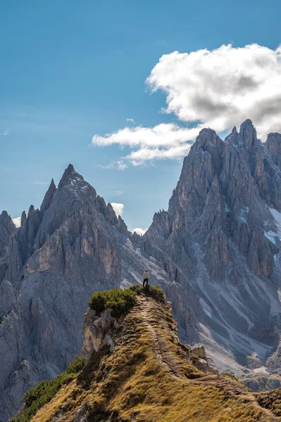 Man enjoying the top of the mountain, overlooking a snowy range, Dolomites Italy