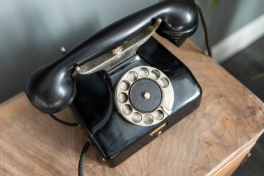 Masanın üzerinde eski siyah bir telefon var.
