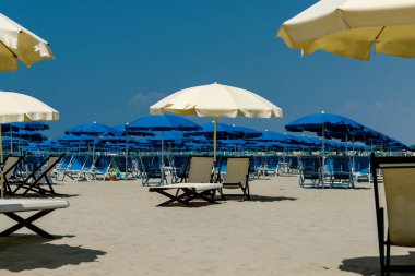 İtalya 'da güneşli yataklı, şemsiyeli ve sarı kumlu bir sahil. Tatil kavramı.