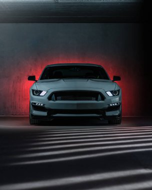 Garajda ön ve arka farları olan modern bir spor arabanın ön görüntüsü.