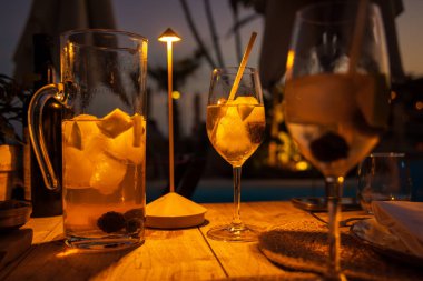 Restoran masasında gün batımına kadar dayanan soğuk yaz kokteyli. Sangria - geleneksel İspanyol içeceği.