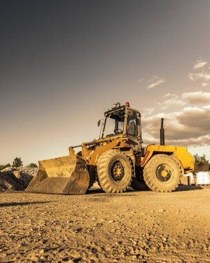 İnşaat alanında ağır tekerlek yükleyici var. Modern güçlü ekipmanlar çalışıyor.