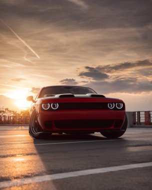 Otoparkta gün batımında güçlü kırmızı spor araba.