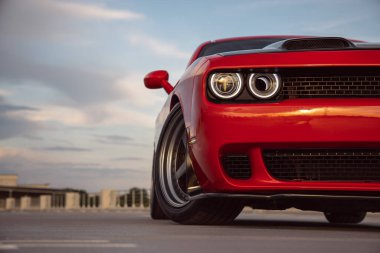 Otoparktaki güçlü kırmızı bir spor arabanın ön görüntüsü.