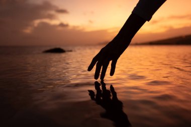 Gün batımında sakin su yüzeyine dokunmak. 