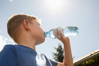 Küçük çocuk ve çocuk yaz sıcağında su içiyor.. 