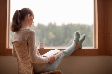 genç kadın evde rahatlatıcı bir kitap okuma. 