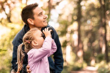 Baba ve kızı birlikte ormanda keşfe çıkıp vahşi yaşam kuşlarına bakıyorlar. 