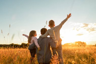 Baba ve çocukları gün batımında bir tarlada yürüyüp birlikte vakit geçiriyorlar. Doğada, aile geleceğinde, tek ebeveyn kavramında..