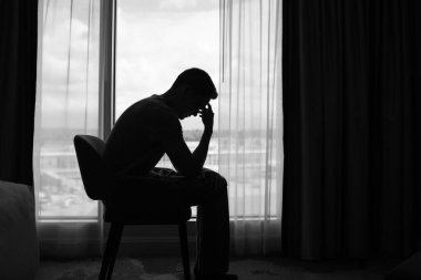 Çaresizlik düşünceleriyle dolu karanlık bir odada üzgün bir adam. Düşünceli üzgün bir adamın portresi. Korku, üzüntü, istismar, depresyon, bağımlılık.