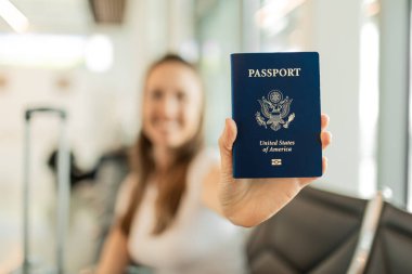 Mutlu gülümseyen genç bayan gezgin havaalanında Amerikan pasaportu taşıyor..