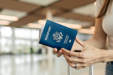 Havaalanı kontrolünde bekleyen bir yolcu, elinde ABD pasaportuyla bekliyor..
