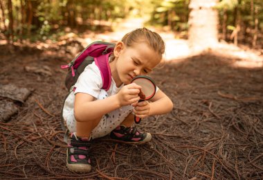 Küçük meraklı kız ormanda büyüteç kullanıyor, çocuk keşfi maceraları, doğa konseptini öğreniyor.