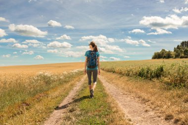 Mutlu kaygısız gezgin kadın güneşli bir günde güzel kırlarda yürüyüş yapıyor.