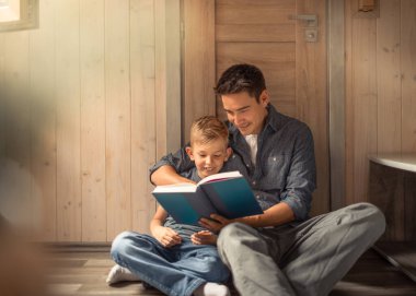 Ebeveyn ve çocuk evde kitap okuyor, aile hayatı, iyi ebeveynlik. 