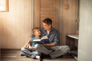 Baba oğluna kitap okuyor. Ailece vakit geçiriyor. Aile eğitimi konsepti.