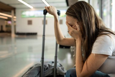Onu yeniden-scheduled/gecikmeli uçuş ile bavulunu bir Uluslararası Havaalanı'nda bekleyen yorgun kadın yolcu