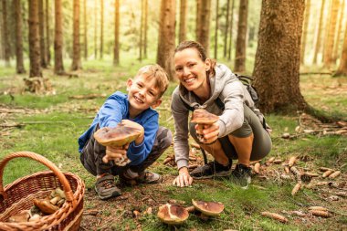 Anne çocuk ormanda sepetli mantar topluyor, mantar toplama mevsimi, aile doğa aktiviteleri.
