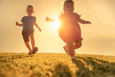 Parkta koşuşturan küçük kız ve oğlan, mutlu çocukluk konsepti. 