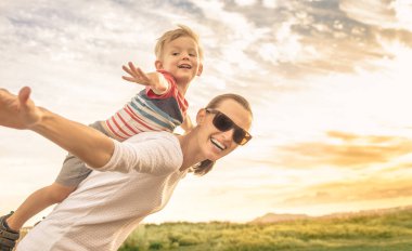 Mutlu anne ve küçük oğlu birlikte eğleniyor özgürce uçuyor gibi yapıyor 