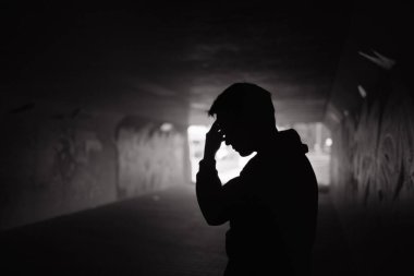 Bunalımlı evsiz üzgün adam Karanlık şehir caddesinde yürüyor