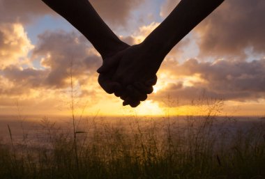 Gün batımında el ele tutuşan çift 