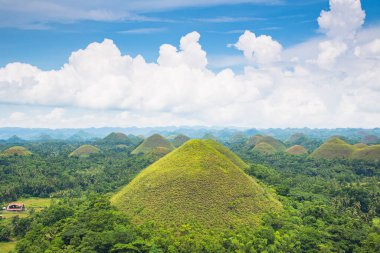 Güzel çikolata tepeleri, mavi gökyüzü, bulutlar ve Filipinler 'deki Bohol adası büyüklüğünde küçük bir ev.