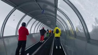 Val Thorens, France - January 15, 2023: skiers in covered conveyor belt type lifts