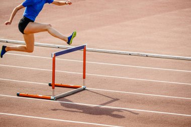 female athlete hurdling at stadium