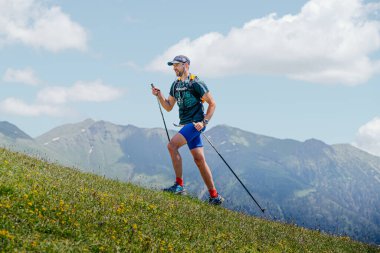 Arkhyz, Russia - July 3, 2022: male athlete walking uphill trail in Arkhyz X Run clipart