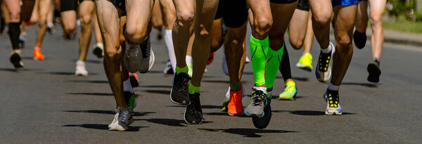close-up legs runners athletes running city marathon, male jogging race in asphalt road, athletics competition