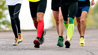 Grup koşucuları maraton koşucuları, ön görüş koşucuları sıkıştırma çorapları ve kineso bant diziyle koşucular