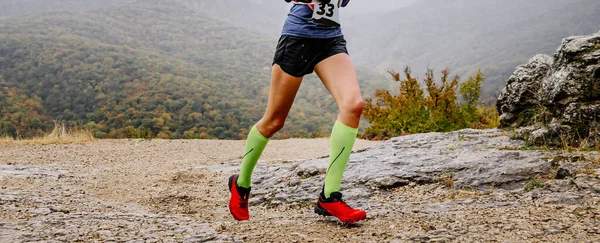 长腿女赛跑选手穿着压缩袜跑山径马拉松 在多云的秋天里跑步穿过山区 — 图库照片